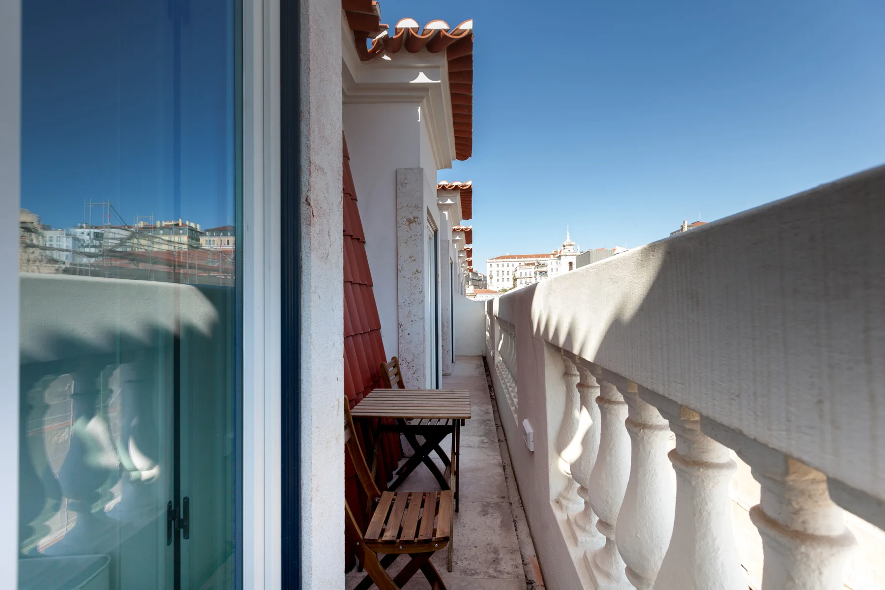 Un balcón estrecho con asientos de madera junto a las ventanas del apartamento.