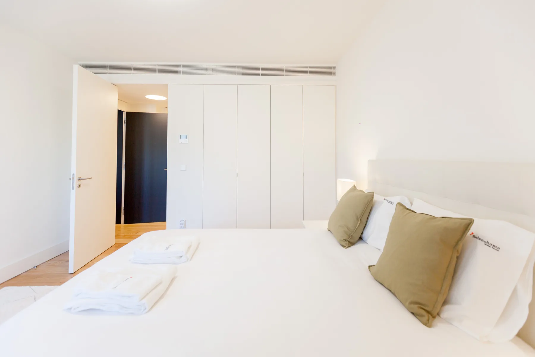 Un dormitorio con una cama grande y armarios empotrados blancos.
