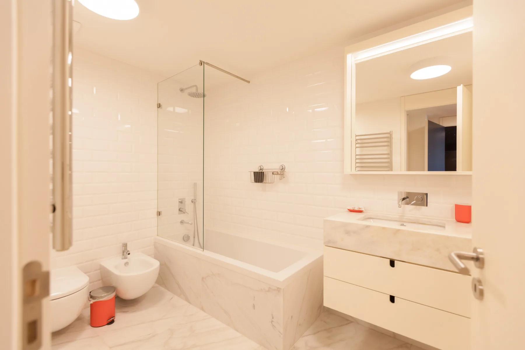 Un baño luminoso con bañera, ducha de pared y tocador.