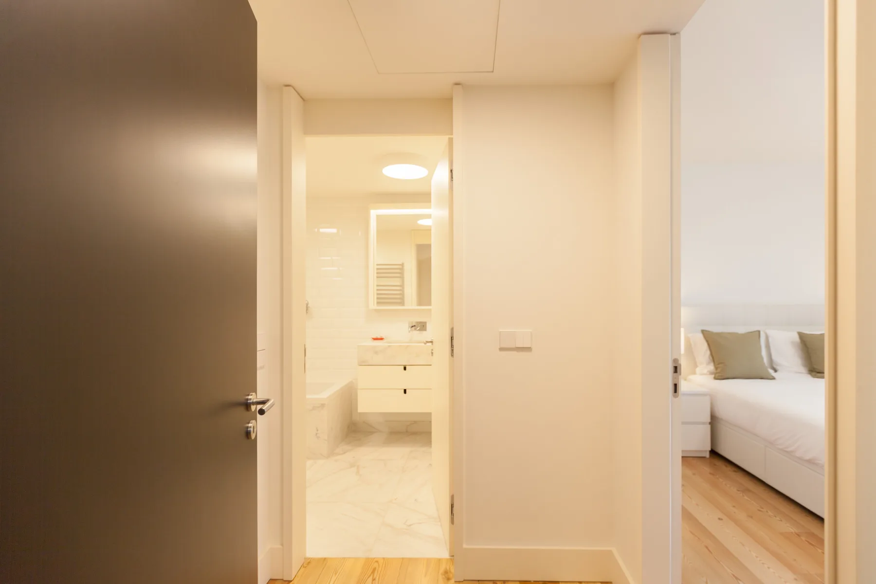 Un pasillo luminoso del apartamento da a un baño y un dormitorio.