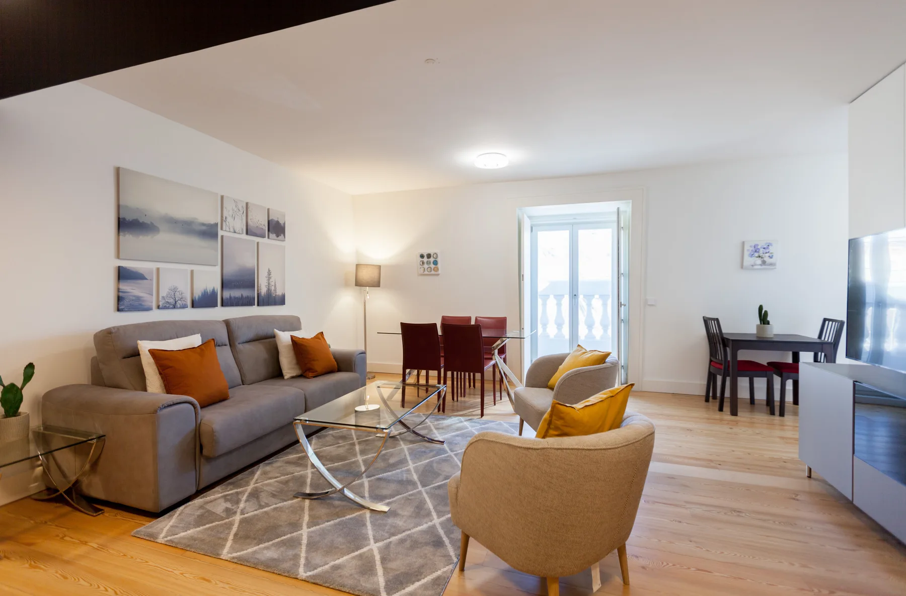 Una sala de estar con asientos, una mesa de comedor y una puerta al balcón.