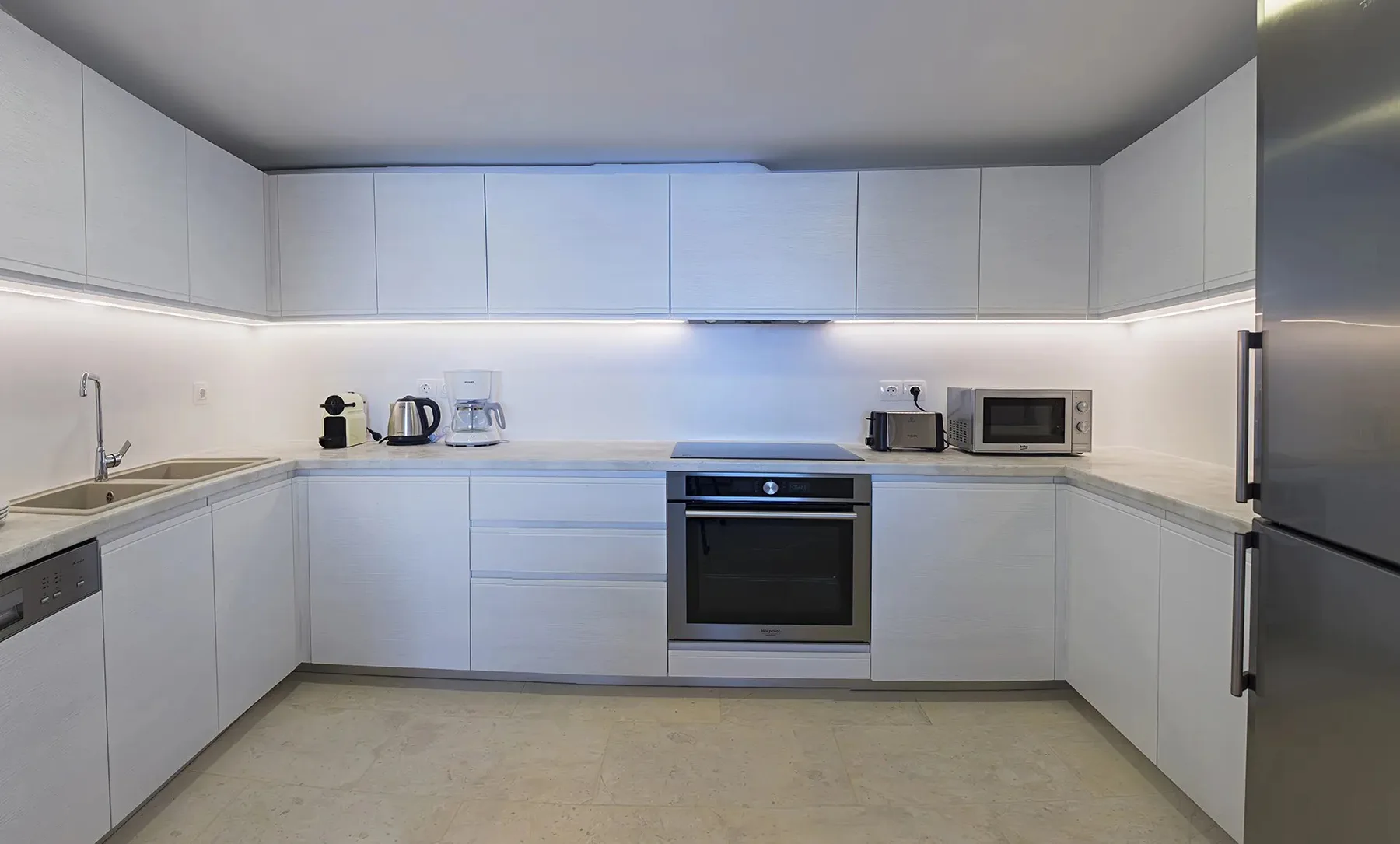 A modern kitchen with white cabinets and built-in appliances.