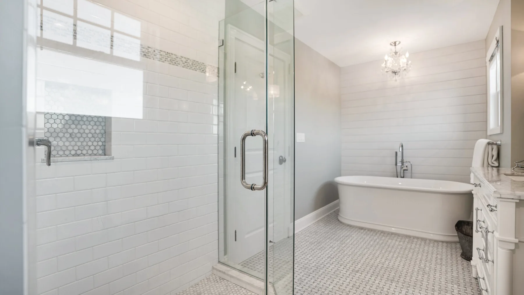 Un baño luminoso con ducha de vidrio y bañera exenta.