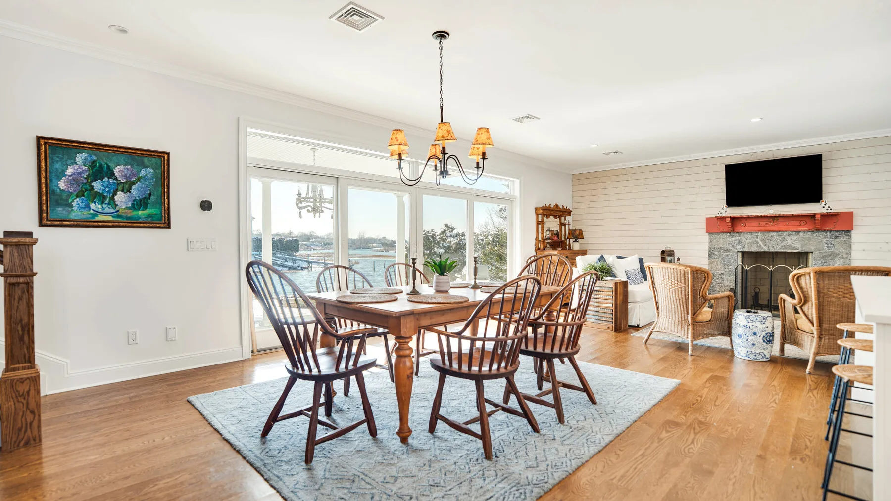 Un comedor y sala de estar luminosos con una mesa de madera, sillas y chimenea.