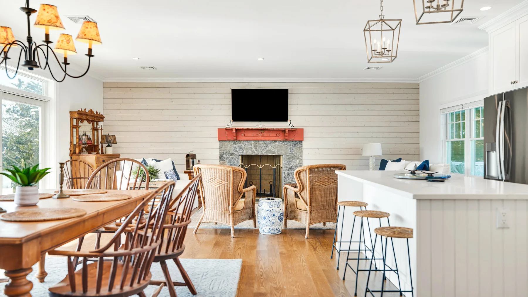 Un luminoso comedor con cocina abierta tiene una larga mesa de madera y una isla blanca.