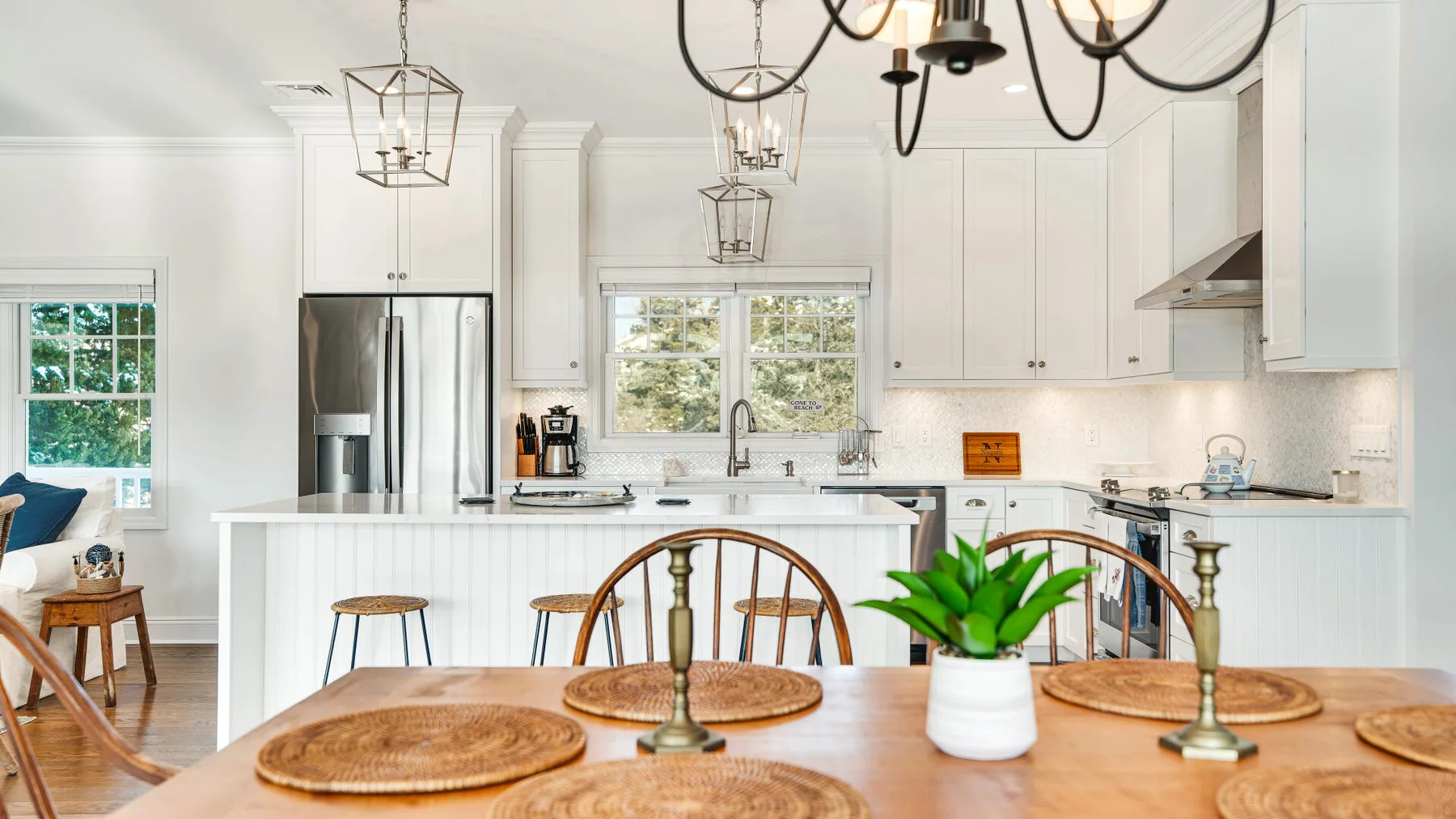 Una cocina luminosa con una mesa de madera y ventanas grandes.