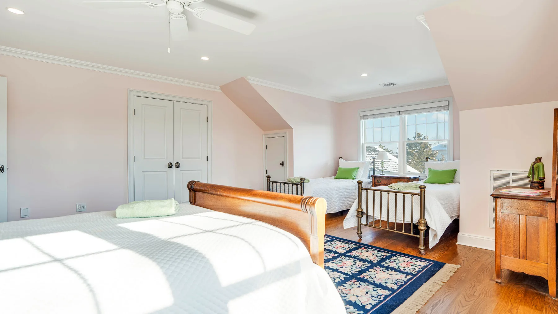 Un dormitorio luminoso con una cama, una ventana y una cómoda de madera.