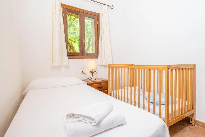 A bedroom with a wooden crib beside a bed and a window.