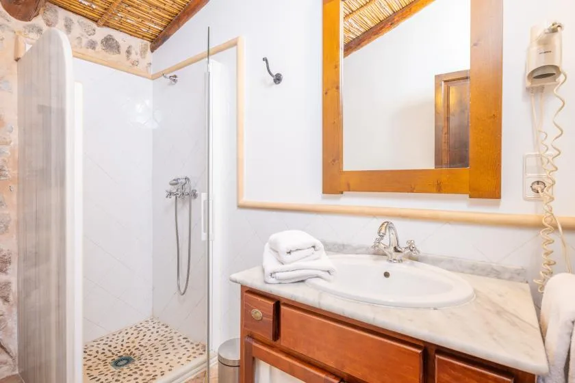 A bathroom with a glass shower, sink, and wooden vanity.