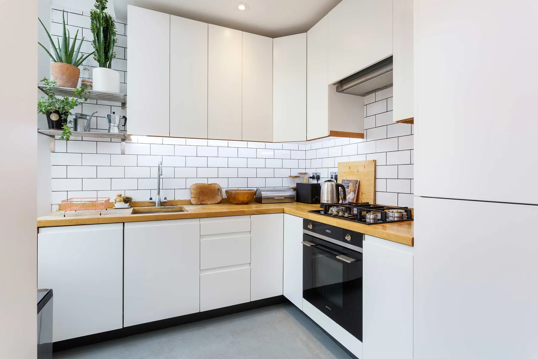 A bright kitchen with white cabinets, tiled walls, and a countertop.