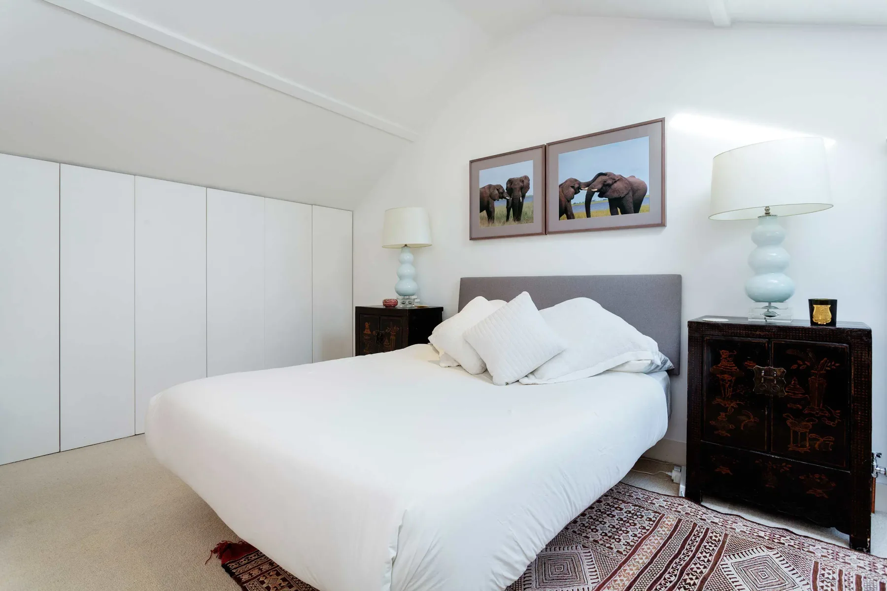 A bright bedroom with a white bed and framed animal pictures above the headboard.