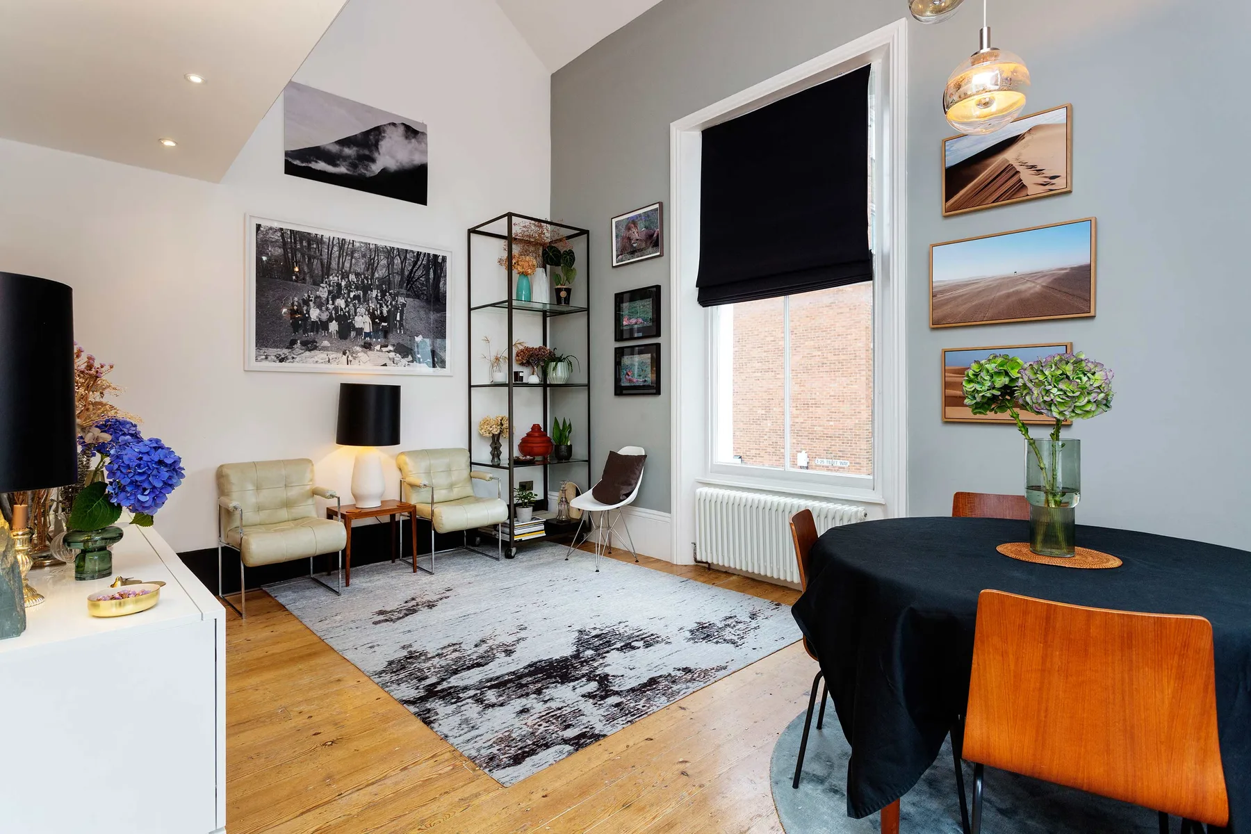 A dining and sitting room with a table, seating, and framed wall art.