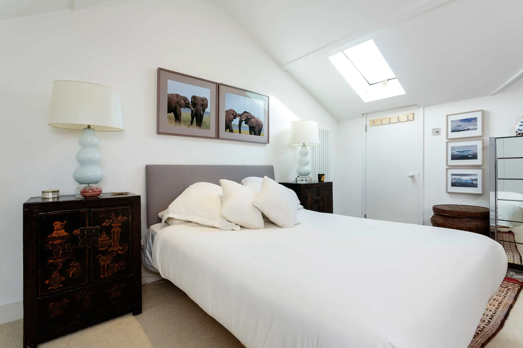 A bright bedroom with a neatly made bed beneath a sloped ceiling.