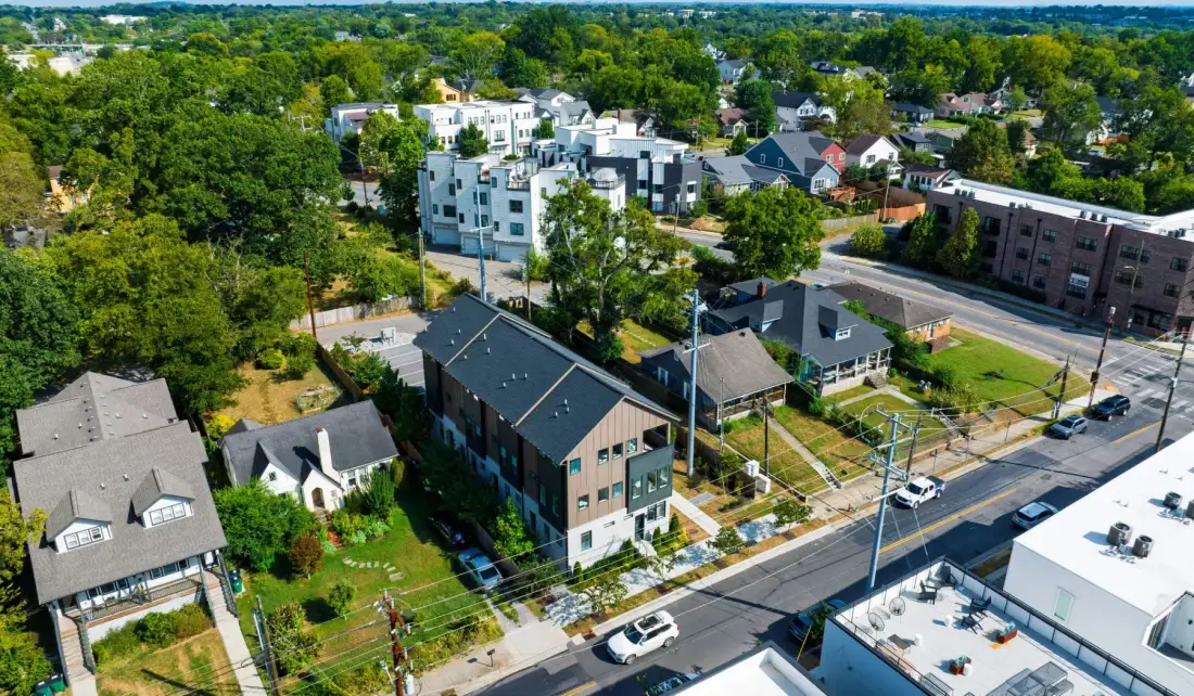 Vista aérea de un barrio arbolado con casas, edificios de apartamentos y calles.