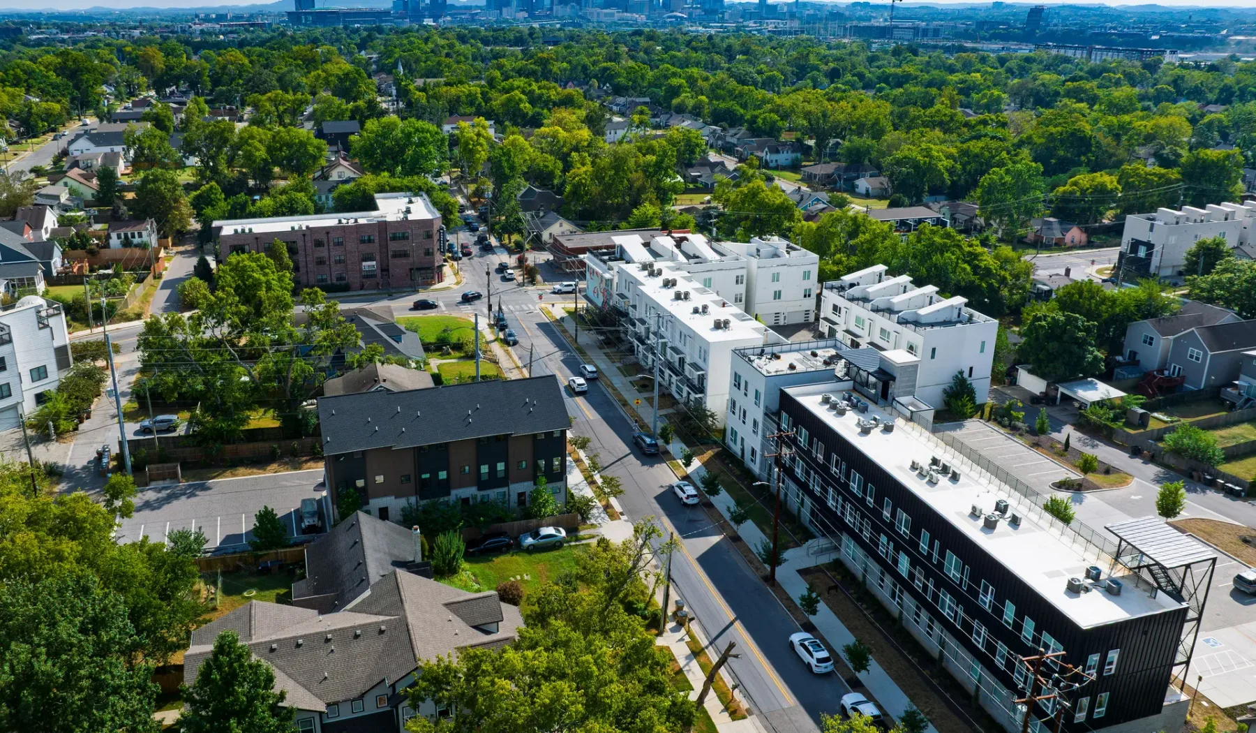 Vista aérea de un barrio residencial con edificios de apartamentos y calles arboladas.