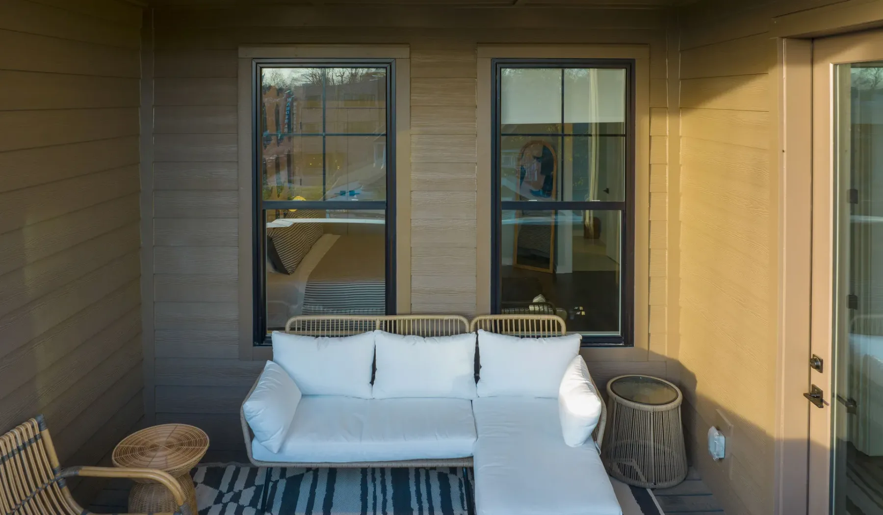 Un patio cubierto con un sofá blanco y ventanas en la pared.