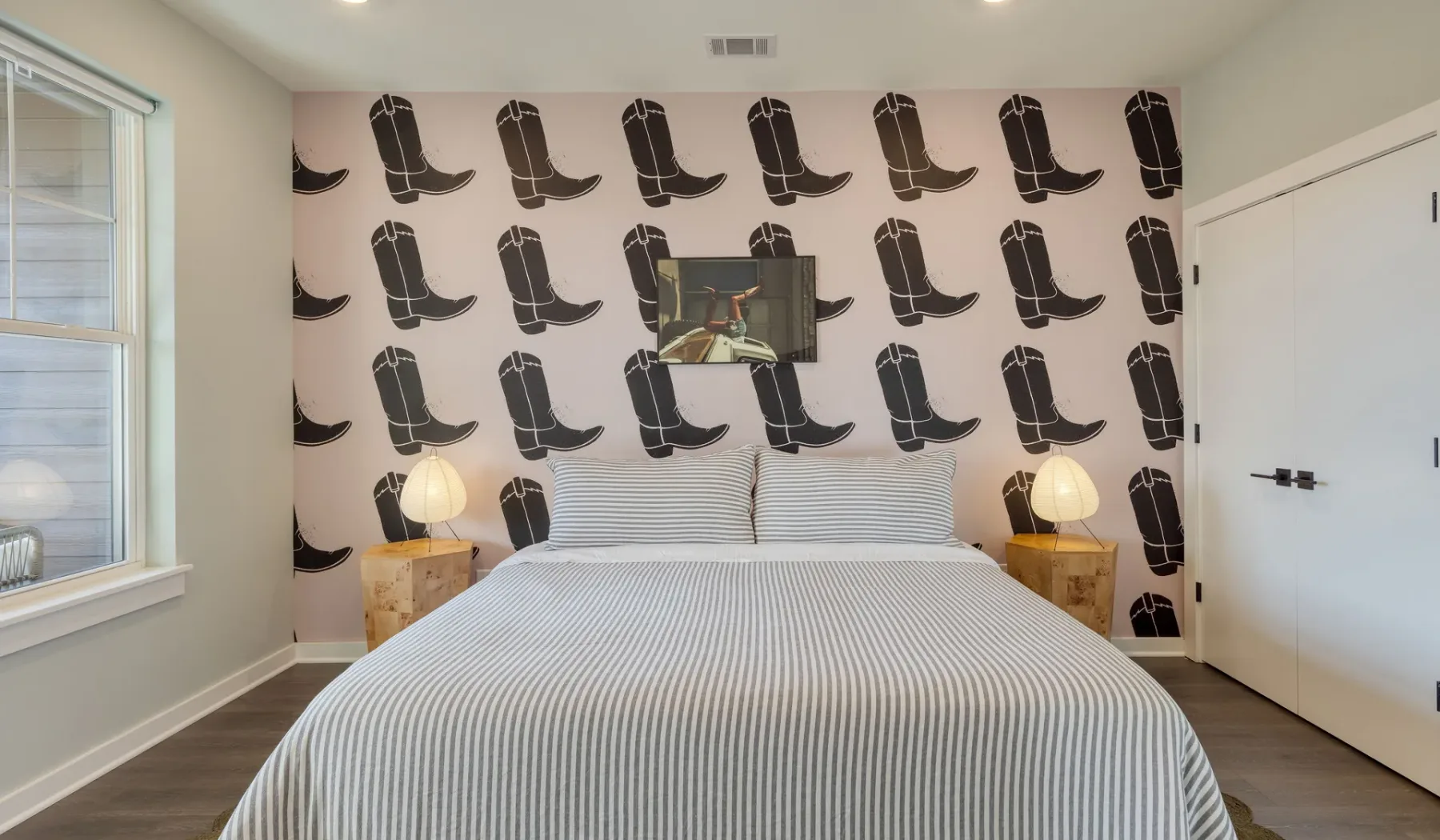 Un dormitorio con una cama bien tendida y papel tapiz con estampado de botas.