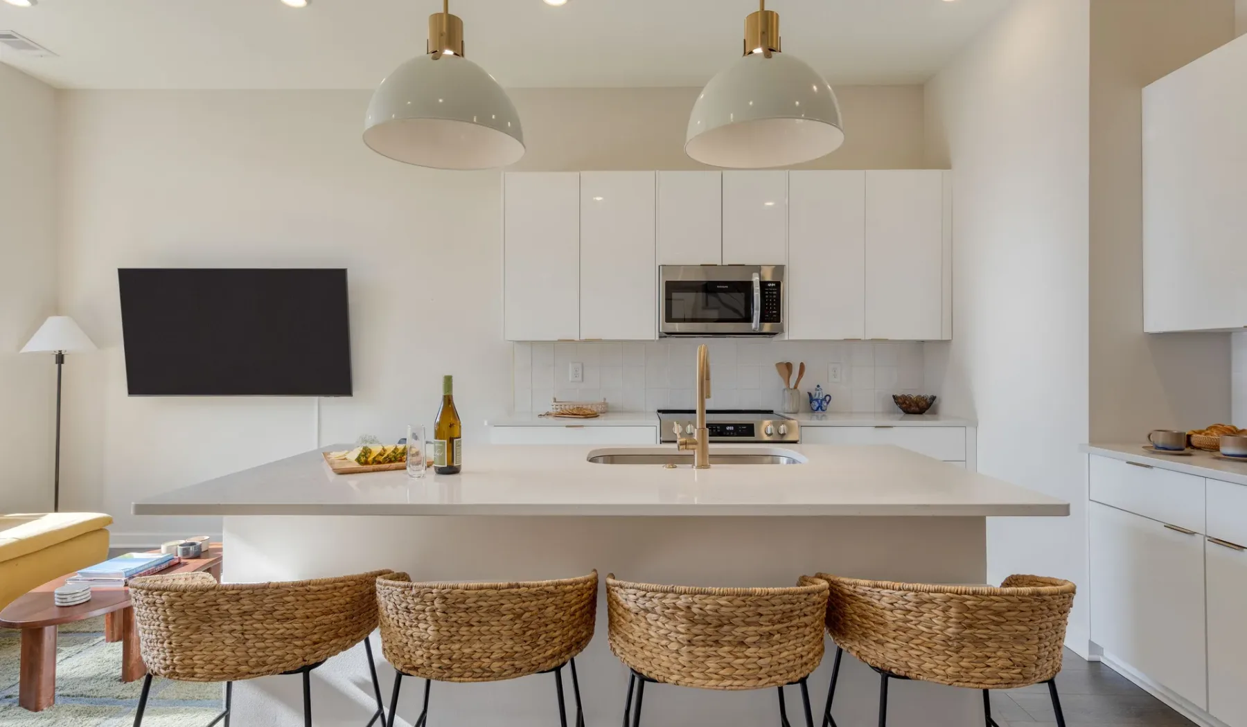 Una cocina luminosa con una isla blanca y taburetes tejidos.