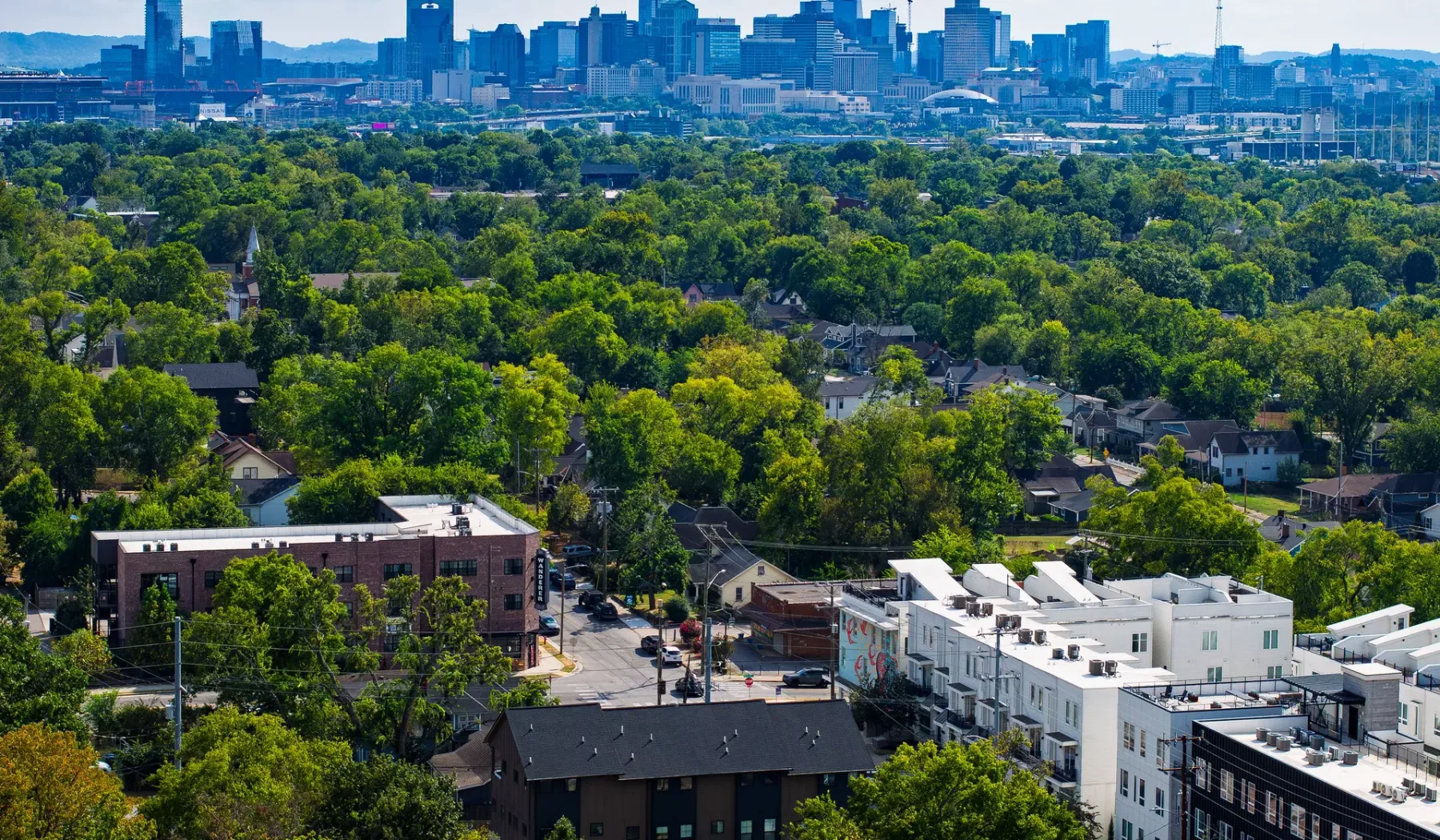 Un barrio arbolado y verde, con edificios de la ciudad a lo lejos.