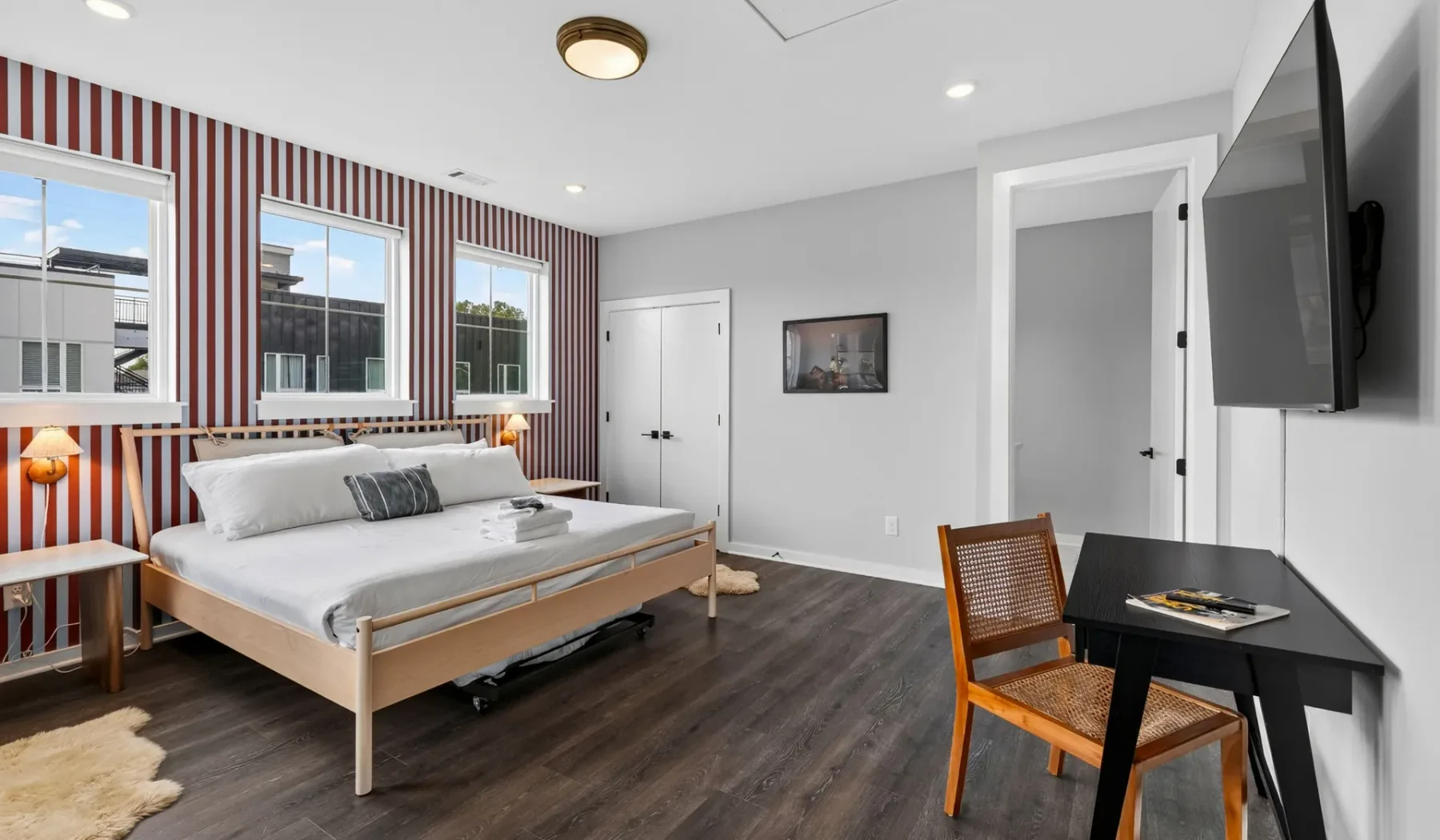 Un dormitorio con una cama, una pared decorativa a rayas y una mesa pequeña con asiento.