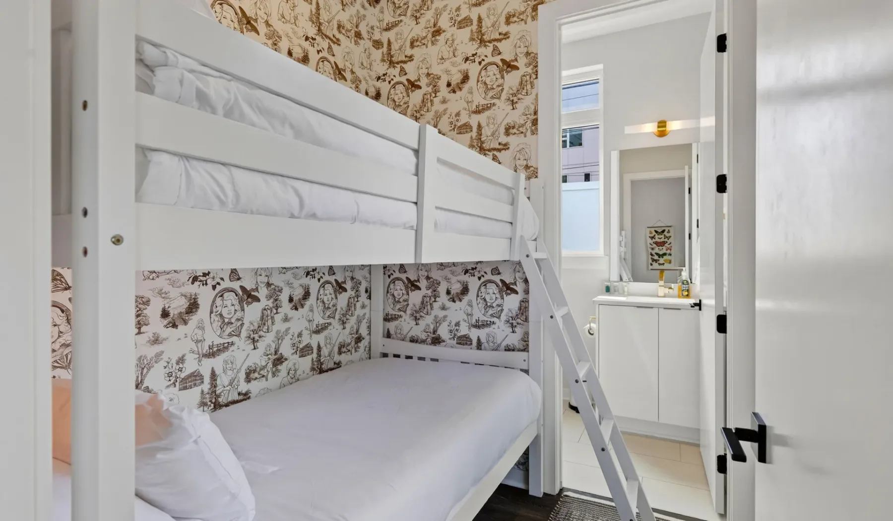 Una litera está en un dormitorio con papel tapiz estampado y un pequeño tocador.