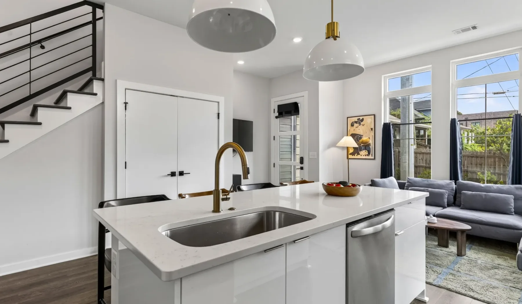 Una cocina luminosa con una gran isla y una sala de estar al fondo.