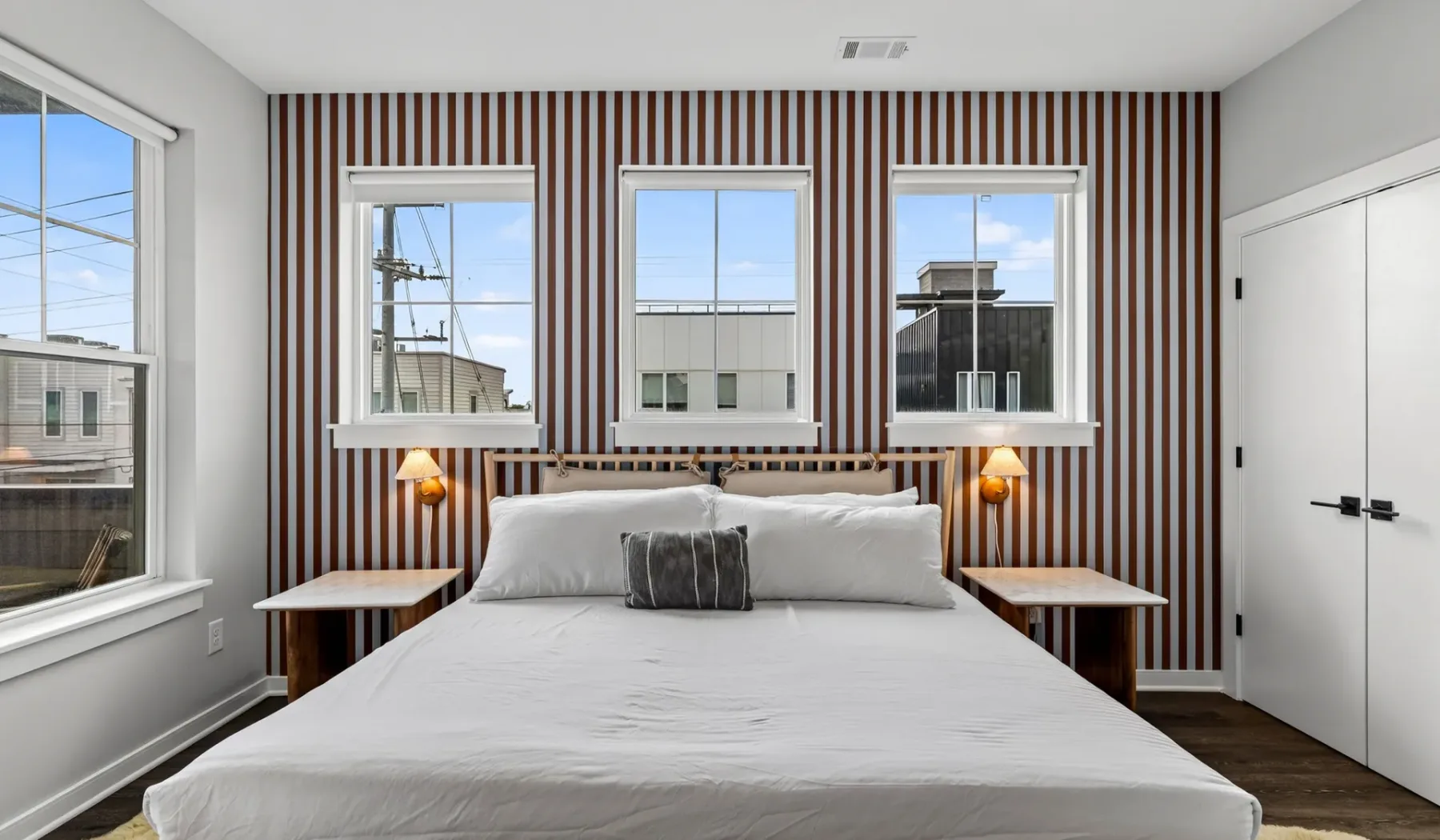 Un dormitorio con una cama grande frente a una pared decorativa a rayas.