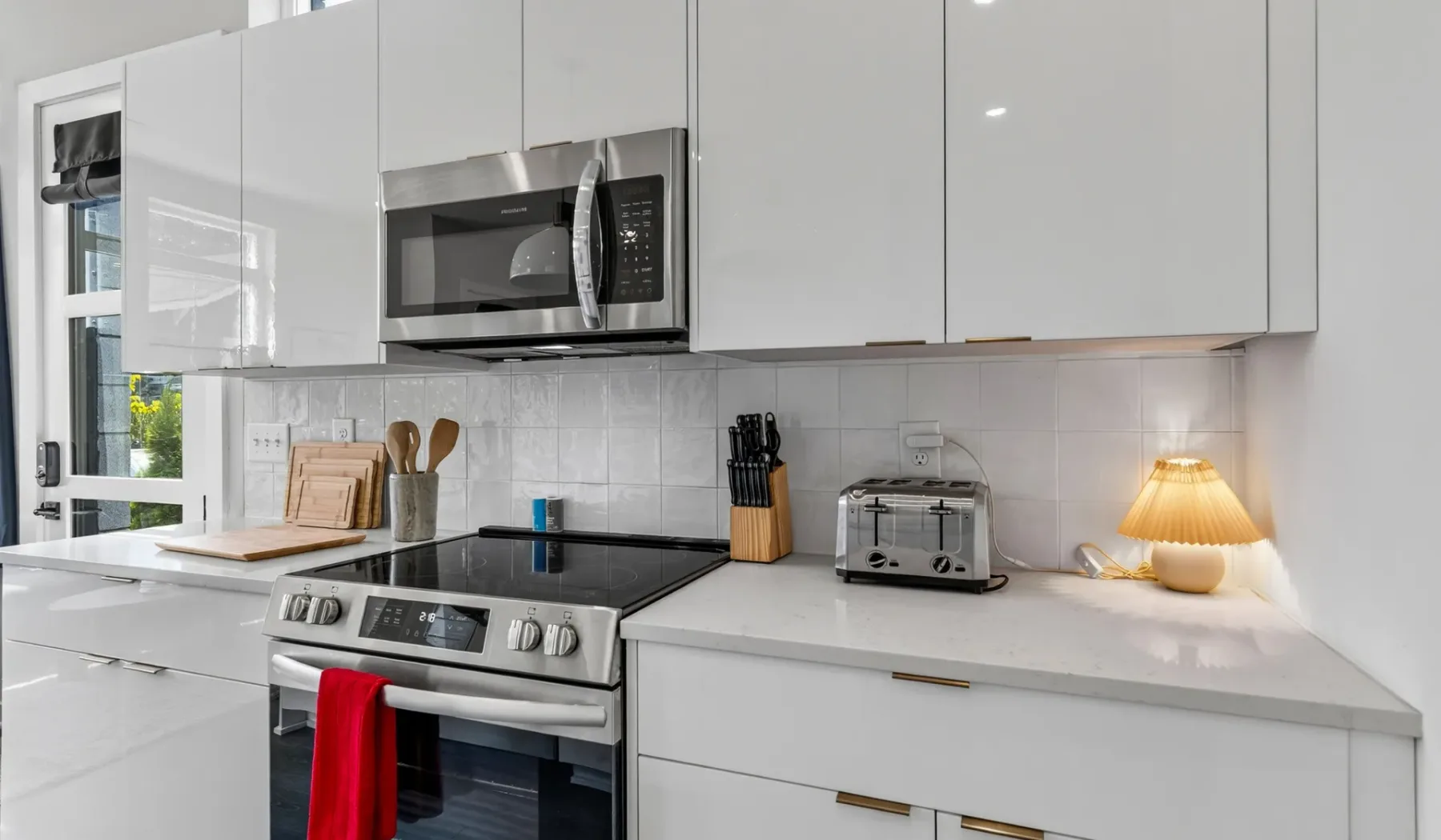 Una cocina moderna y luminosa con gabinetes blancos, una estufa y electrodomésticos sobre la encimera.