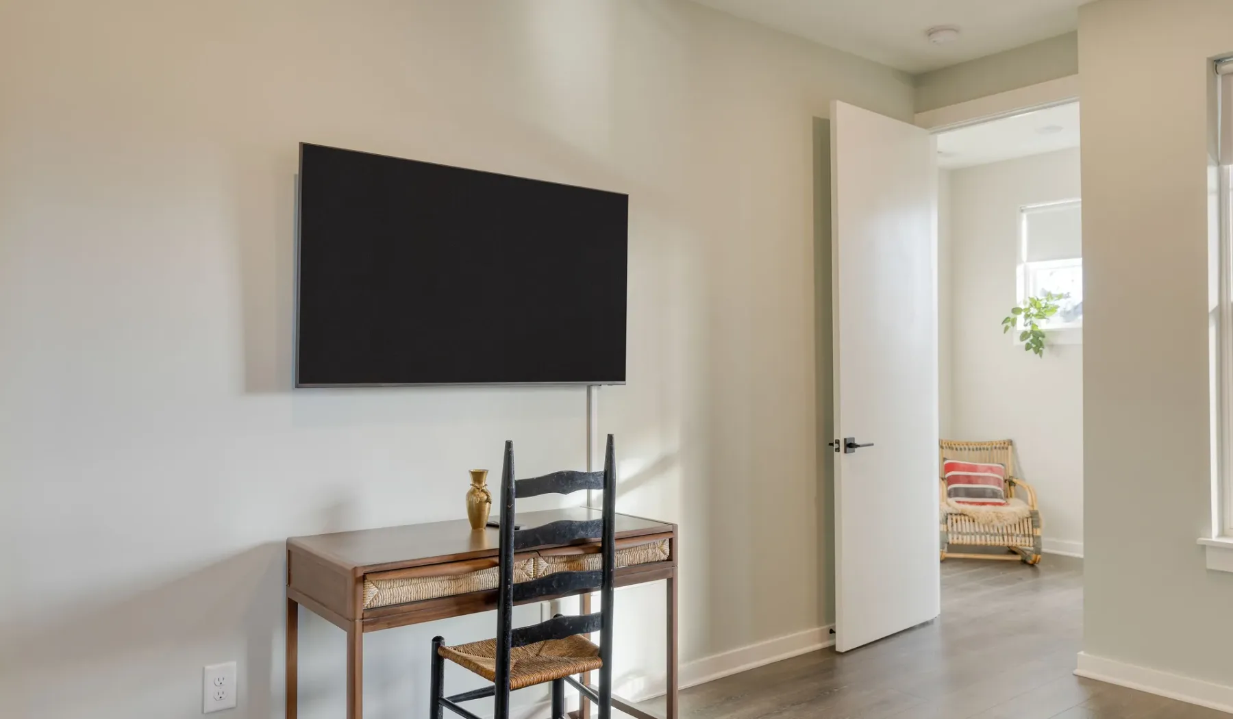 Una sala de estar con un televisor montado en la pared y una puerta abierta.