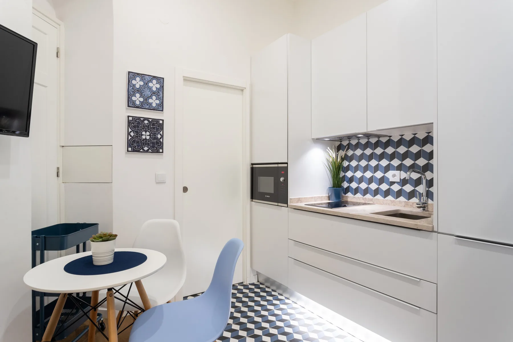 Una cocina compacta con zona de comedor y detalles de azulejos azules y blancos.