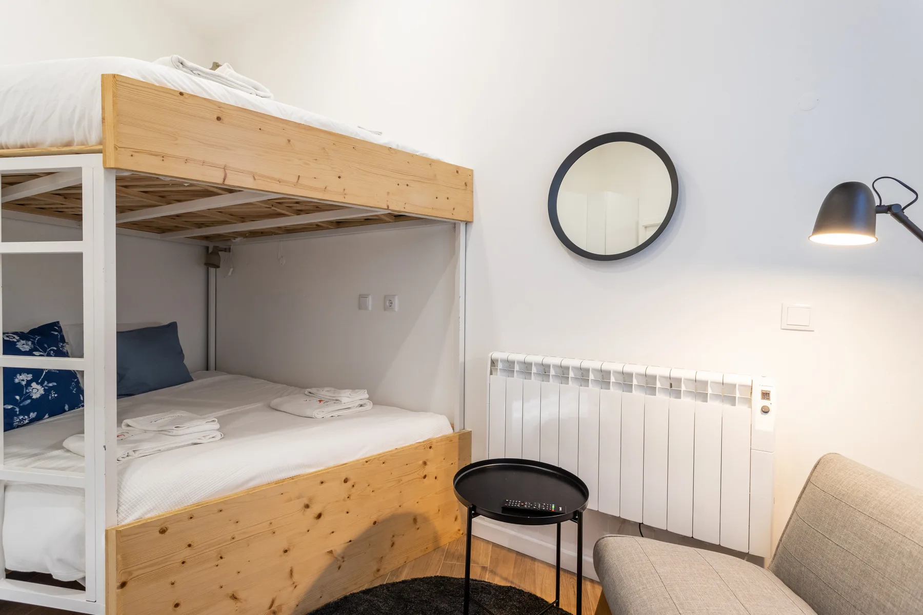 Un dormitorio con una litera de madera, un radiador y asientos.