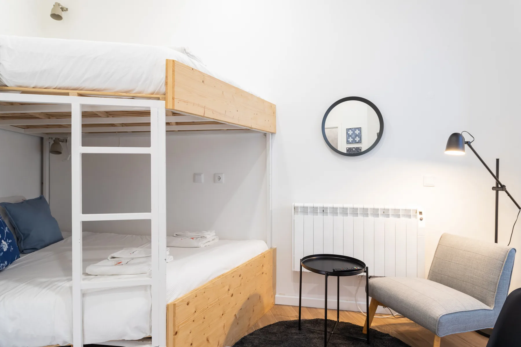 Un dormitorio con literas y un sillón junto a una mesa pequeña.