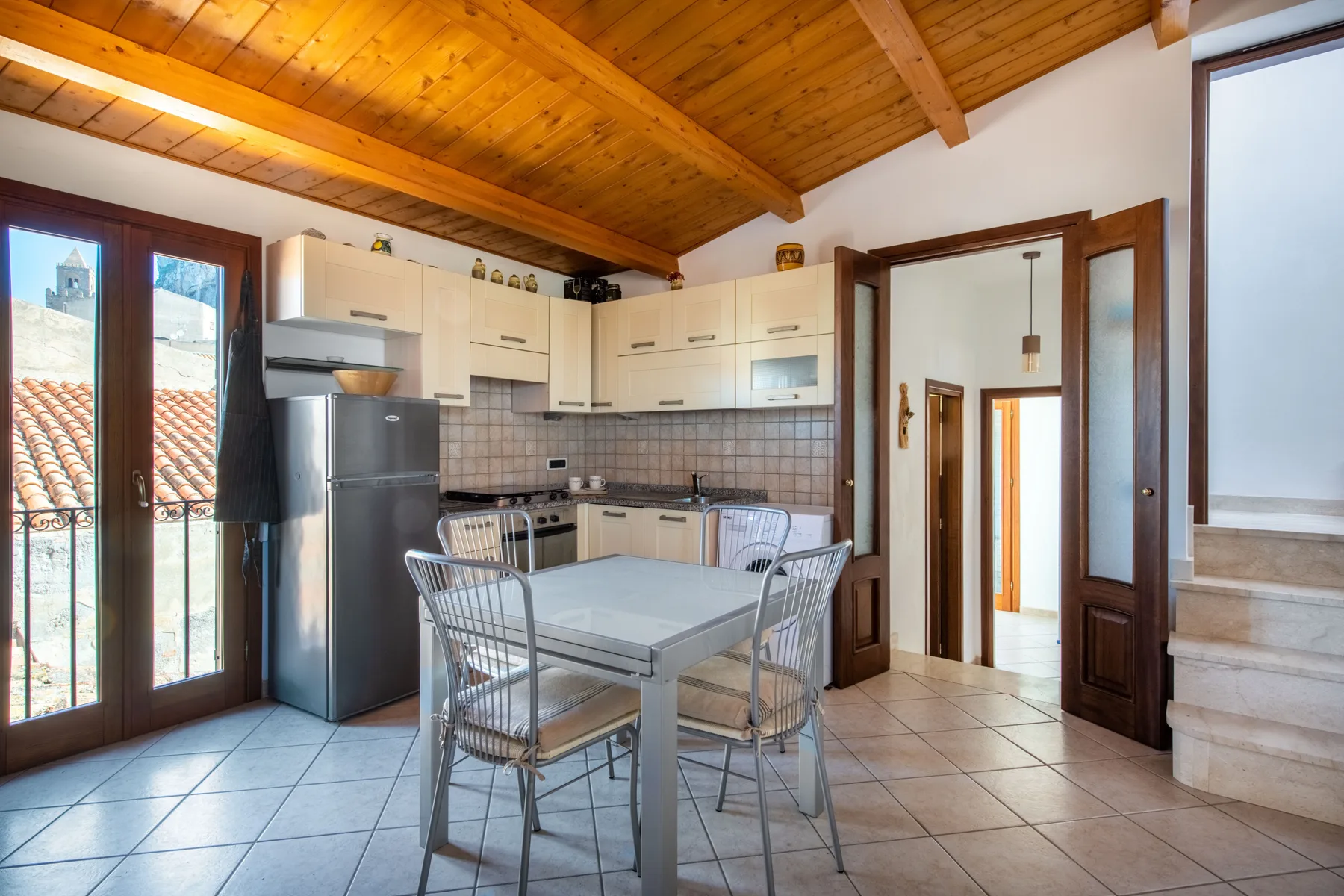 A kitchen and dining area with light cabinets, a table, and a wooden ceiling.