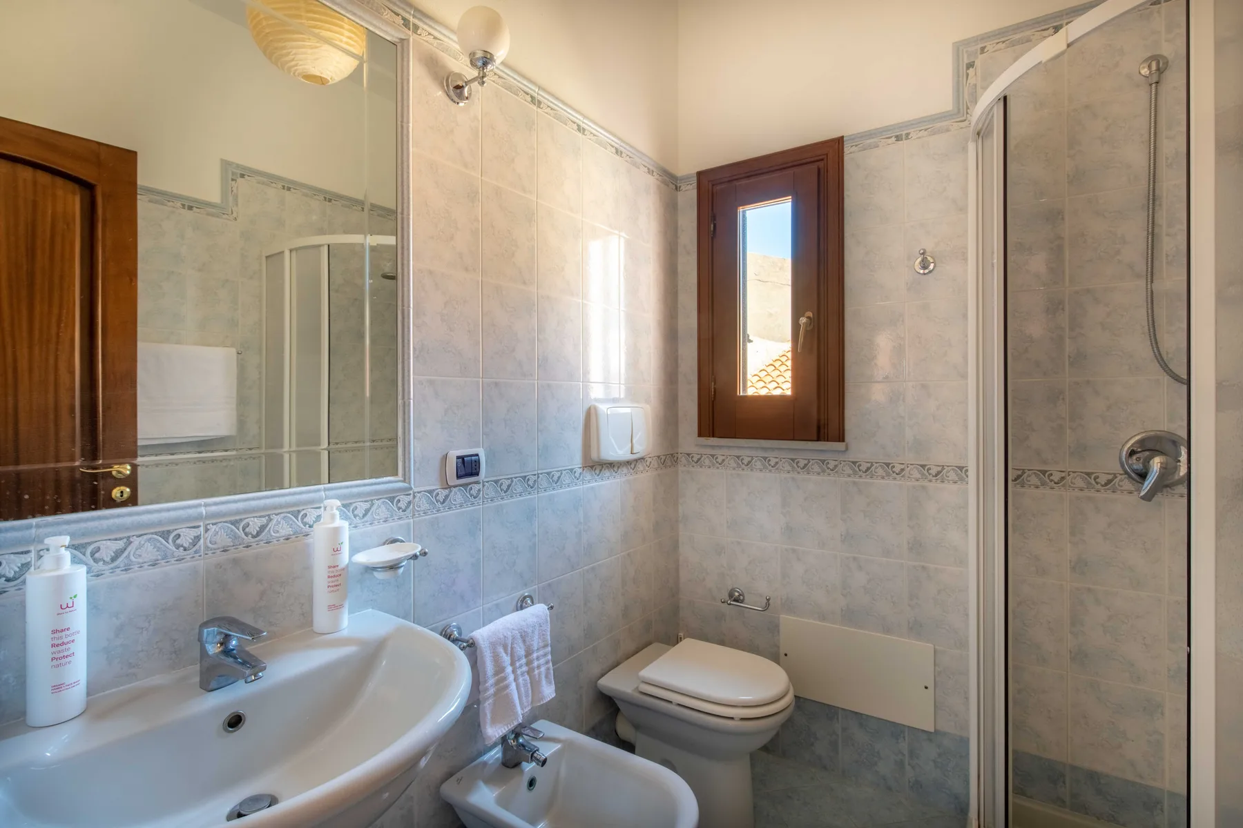 A tiled bathroom with a sink, toilet, and glass shower.