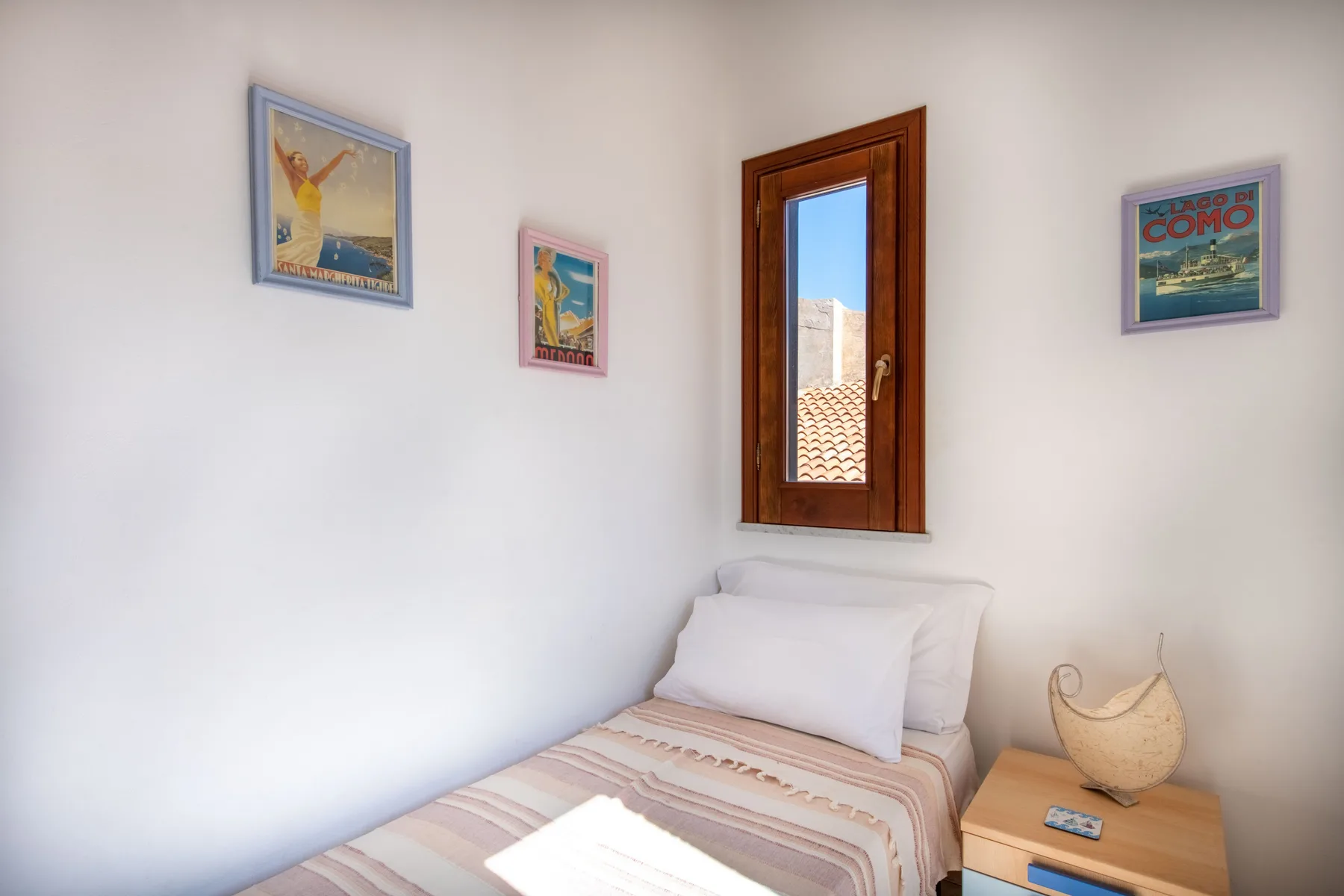 A bedroom with a bed, a small bedside table, and a window.