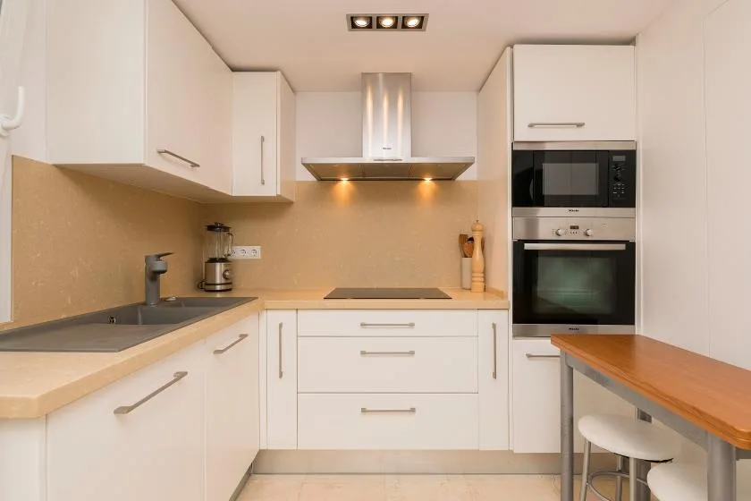 Una cocina moderna y luminosa con armarios blancos, una placa de cocina y una encimera.