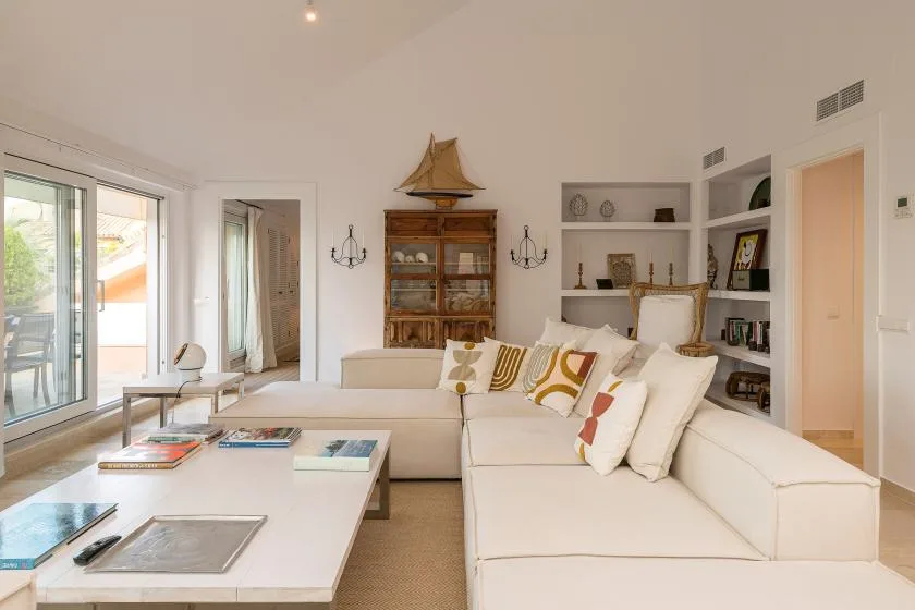 Una sala luminosa con una zona de asientos y una mesa de centro baja.