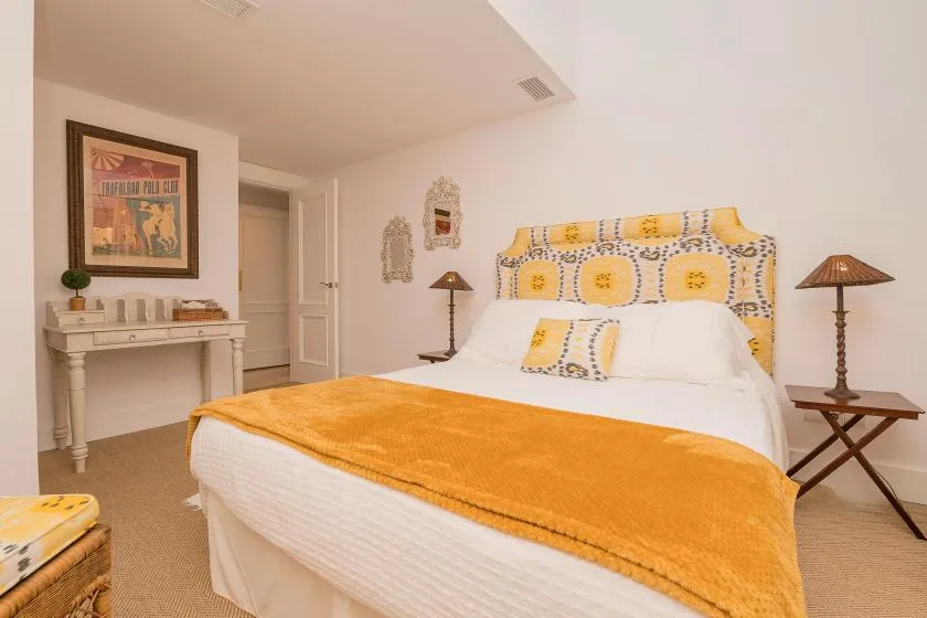 Dormitorio con una cama cubierta por una manta naranja y un cabecero estampado.