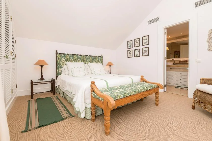 Un dormitorio luminoso con una cama de estampado verde y lámparas de noche.