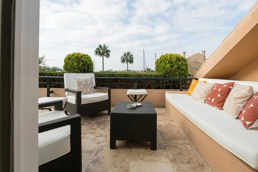 An outdoor terrace seating area with a low table and cushioned benches.