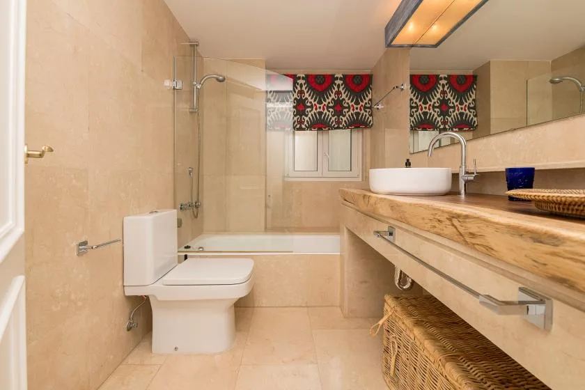 Un baño con bañera, ducha, inodoro y un largo mueble de lavabo.