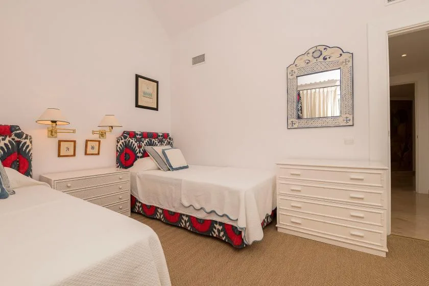 Un dormitorio con dos camas, mesitas de noche y una cómoda.