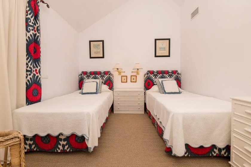 Un dormitorio con dos camas, telas estampadas a juego y una cómoda entre ellas.