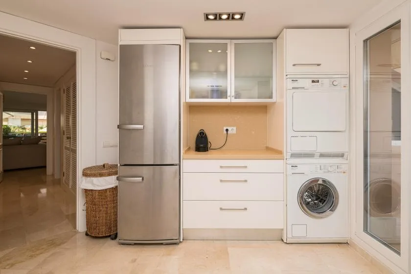 Una cocina luminosa con refrigerador, gabinetes y electrodomésticos de lavandería.