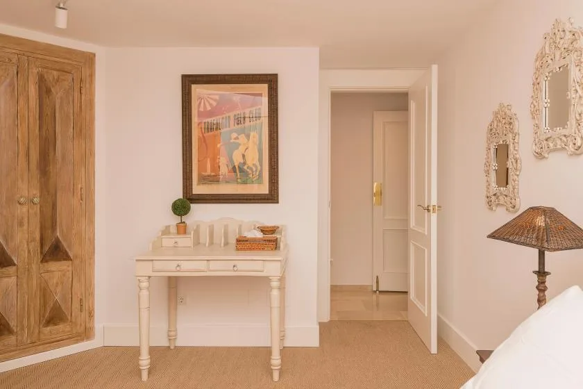Un dormitorio con un armario de madera, una consola pequeña y una puerta abierta.