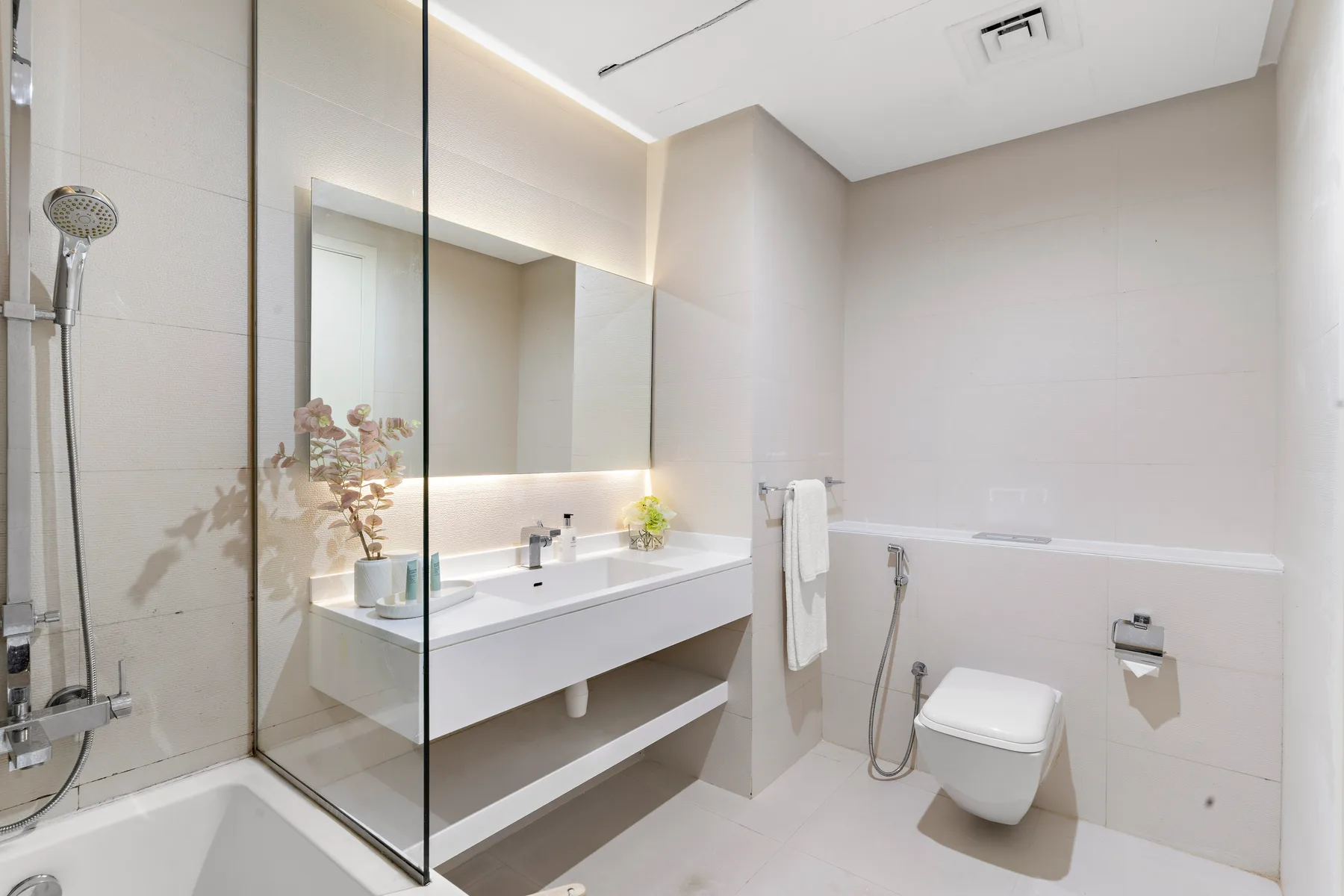 A modern bathroom with a long vanity and a bathtub.