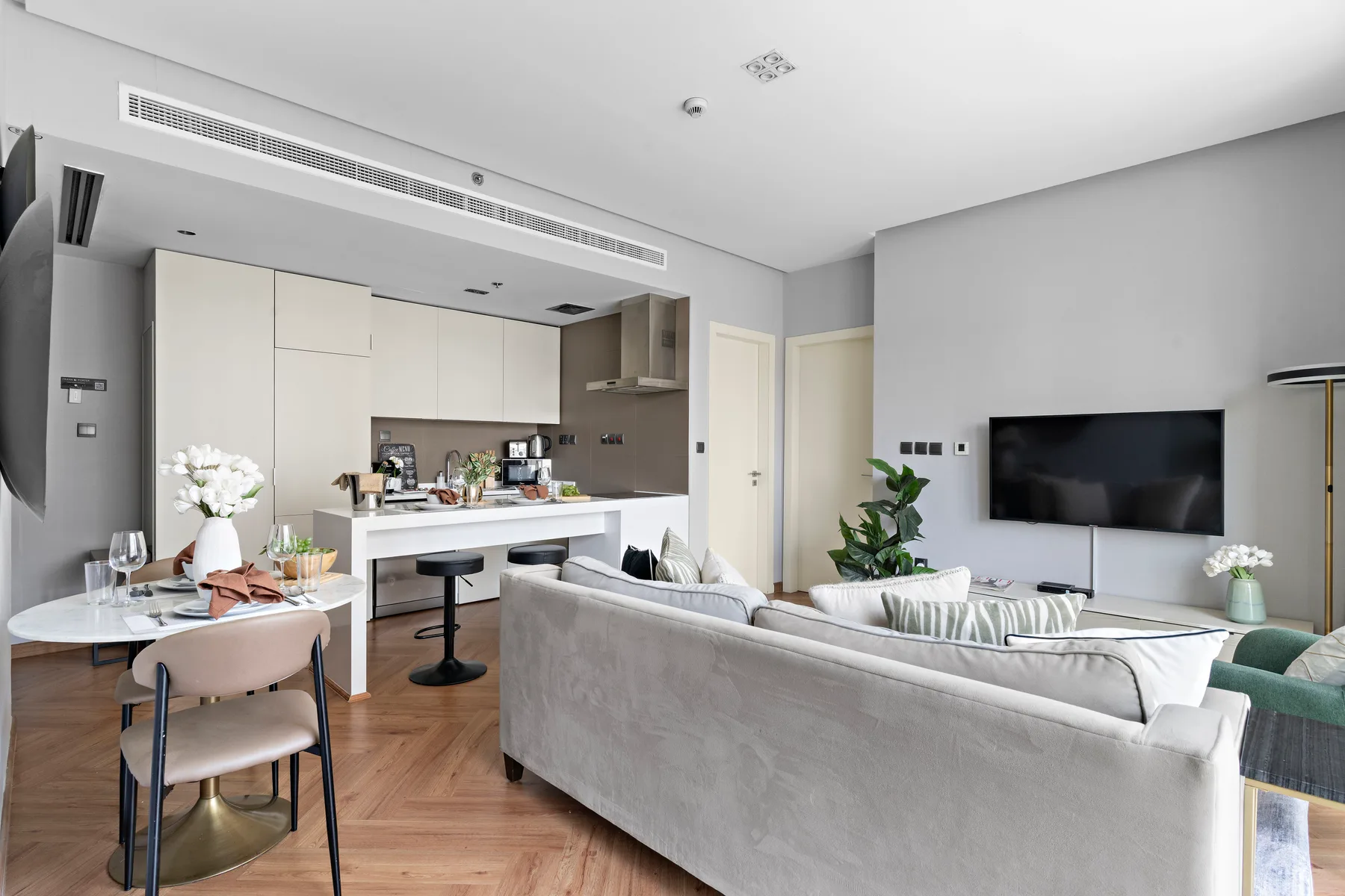 Sala de estar y cocina de concepto abierto, con mesa de comedor y televisor en la pared.