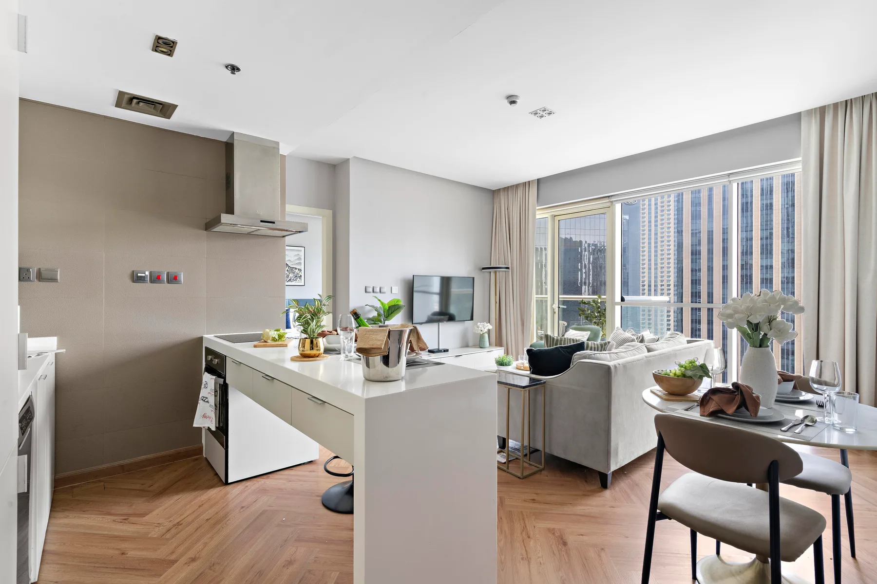 An open-plan kitchen and living area with large windows overlooking nearby buildings.