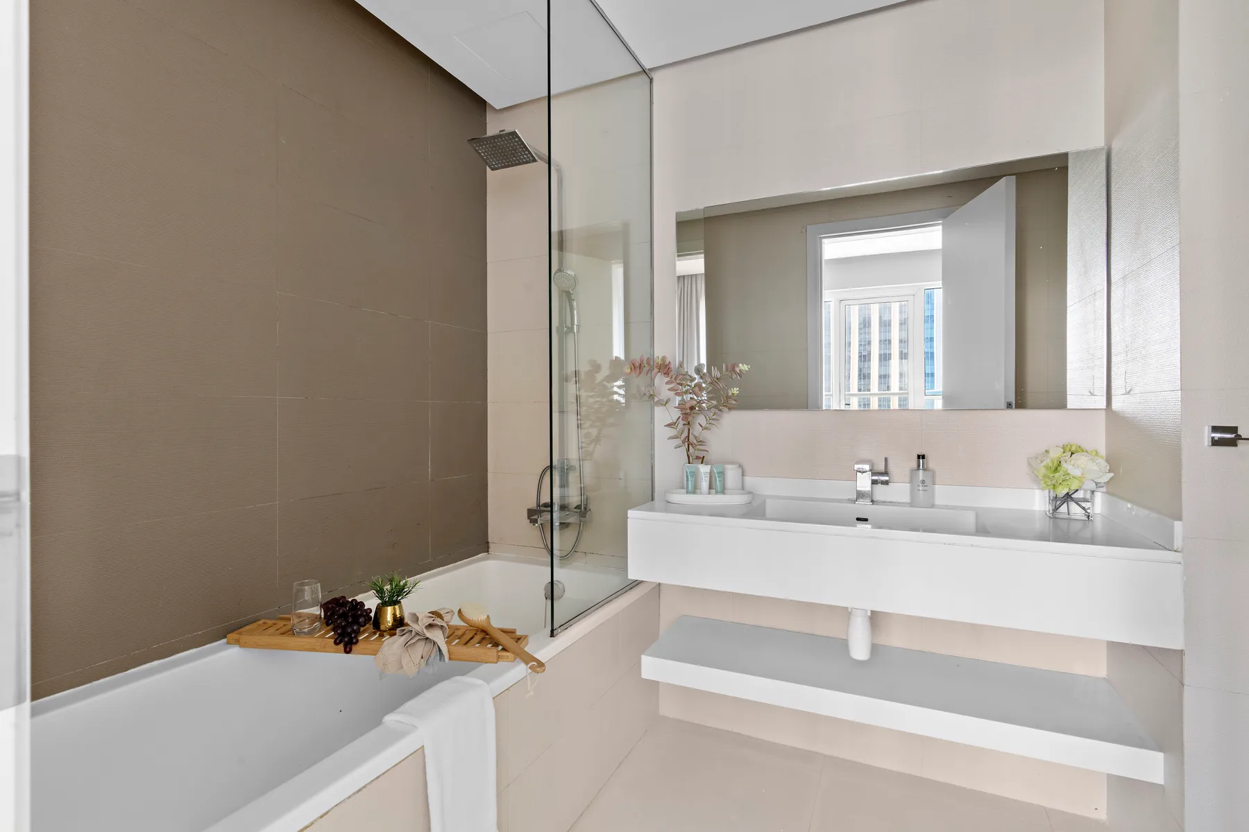 A modern bathroom with a bathtub, glass shower screen, and wide vanity.