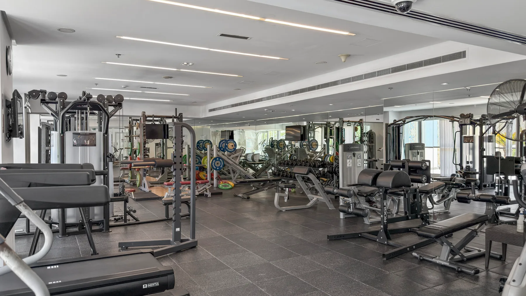 A spacious gym with weight machines, benches, and exercise equipment.